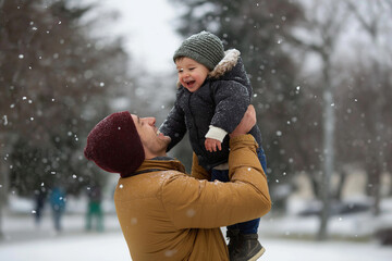 A joyful father lifts his smiling son in the snow, perfectly capturing the essence of family bonding and the happiness found in winter activities and outdoor fun.