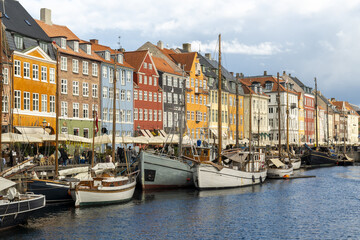View of colorful buildings lining the Nyhavn canal, where boats gently bob in the water, reflecting the charming atmosphere of the city, Copenhagen, Denmark.