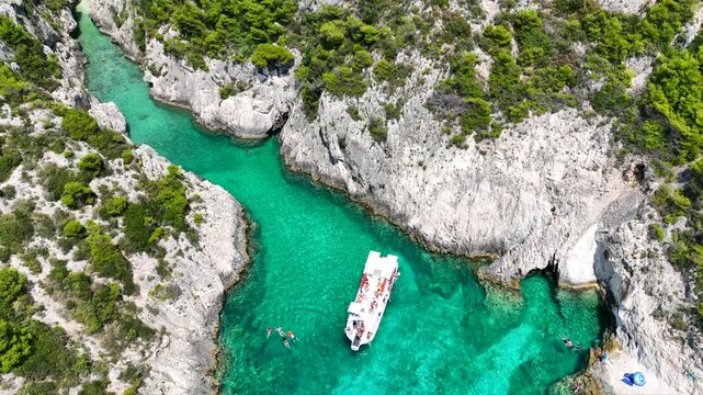 Aerial drone video of of Porto Stenitis famous fjord shaped bay with crystal clear turquoise sea and small beach  ideal for snorkeling visited by small tourist boats, Zakinthos island, Ionian, Greece