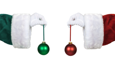 PNG image of Santa hands in green and red suits hold contrasting red and green christmas ornaments against a for holiday design on transparent background