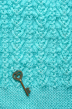 vintage key on knitted textured background sweater. Vintage key on knitted textured background sweater. Fragment of mint color handmade woolen knitted pattern surface. Detail of tracery woven knitwear