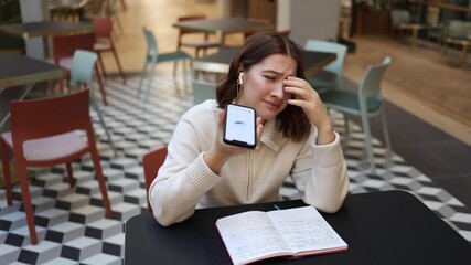Artificial intelligence becomes study companion as frustrated female student admits academic failure holding phone and notebook seeking reassurance motivation and calm focus