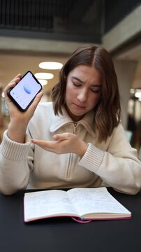 Vertical screen focused student corrects ChatGPT mistake in homework checks notes points at error shows frustration during study indoors