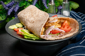 Wholegrain tortilla wraps with vegetables and chicken on a plate.