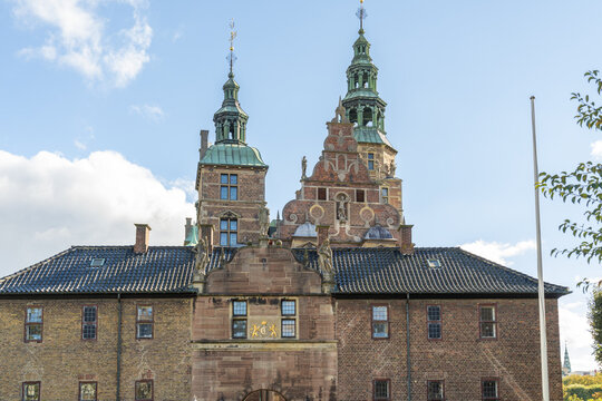 View of the Rosenborg Castle's rich red brick facade rises majestically, topped with aged copper spires against a serene sky, Copenhagen, Denmark.