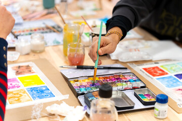Student hand painting watercolor in creative art workshop