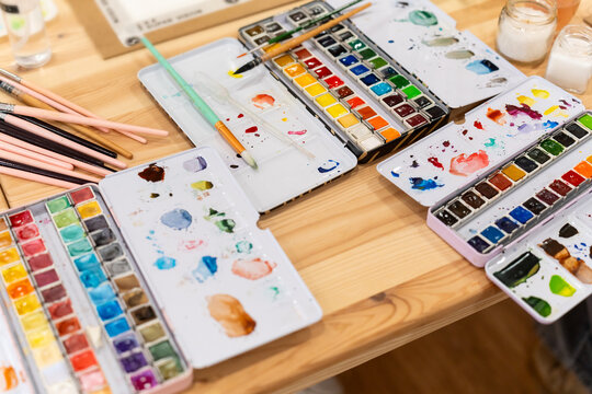 Watercolor painting supplies and palettes on creative wooden desk - Powered by Adobe