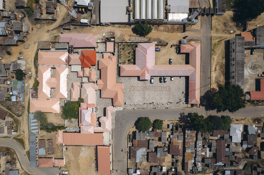 Aerial view of buildings with red roofs and organized structures contrasting with the surrounding dwellings, capturing the urban landscape, New Bussa, Niger, Nigeria.