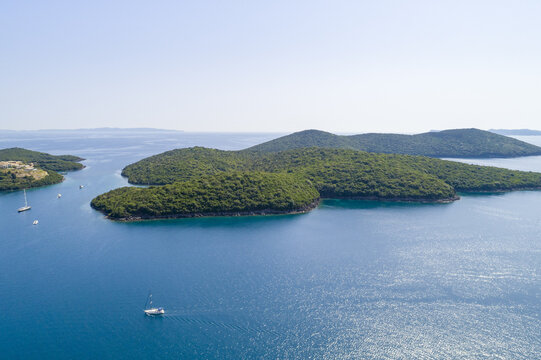 Aerial view of the verdant islands stand as emerald jewels in the Ionian Sea's turquoise embrace, with white yachts dotting the water like delicate brushstrokes, Syvota, Thesprotia, Greece.