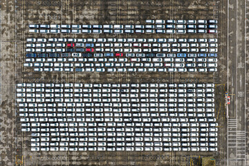 Aerial view of rows of pristine white cars interspersed with a few vibrant red ones on the concrete expanse of Tanjong Pagar Terminal, Singapore, Singapore.