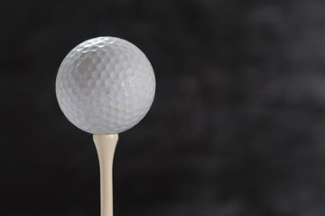 Golf ball on a tee on a black background close-up
