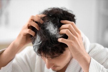 Fototapeta premium Young man with graying hair in bathroom, closeup