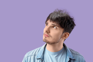 Obraz premium Sad young man with graying hair on lilac background, closeup