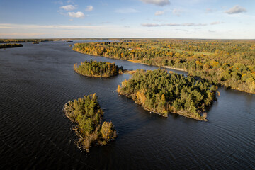 Aerial view of shimmering waters embrace forested islands as autumn's golden touch paints the landscape, Angso, Vastmanland County, Sweden.