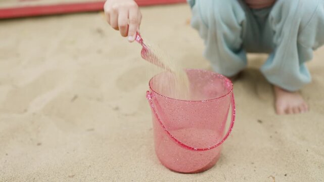 A girl plays in a sandbox on a playground in a park