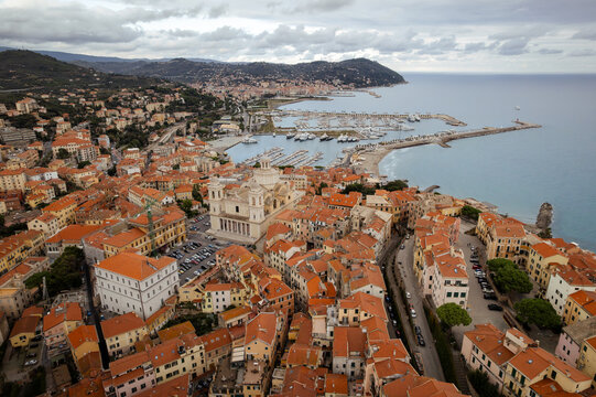 Aerial view of terracotta rooftops cascading towards the azure Ligurian Sea, punctuated by the grandeur of Imperia Cathedral, Imperia, Liguria, Italy.