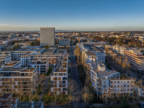 Aerial view of modern buildings and tree-lined streets under a clear sky, contrasting with the distant skyline, Darmstadt, Hessen, Germany.