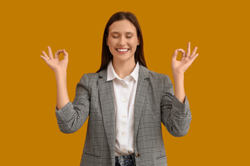 Young businesswoman meditating on yellow background