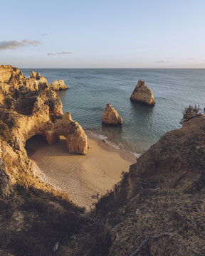 View of golden cliffs embrace a secluded beach where the turquoise sea whispers secrets against the shore, Alvor, Faro District, Portugal.