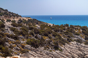 Dramatic diagonal rock strata along a coastal serpentine road, sculpted by tectonic shifts and erosion into striking striped ridges above the turquoise sea. Demre, Turkey, Mediterranean.