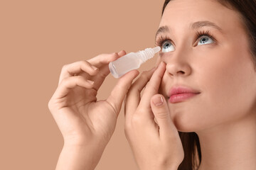 Young woman using eye drops on beige background, closeup