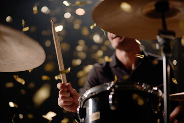 Obraz premium A dynamic image captures a drummer energetically performing amidst a shower of confetti, evoking the excitement and rhythm of live music and celebration.