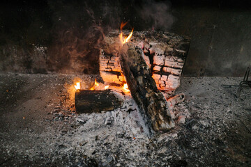 Logs burning alone with fire and embers in a night barbecue