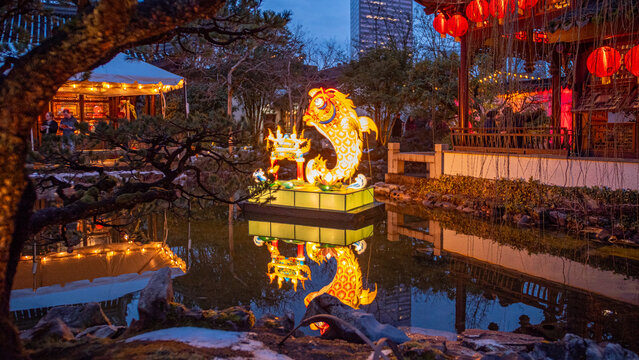 View of glowing lanterns of fish and architecture reflect on the tranquil waters in the Chinese Garden, Portland, Oregon, United States.