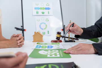 Legal professional explaining ESG investment concepts and sustainable development goals to a client, using a gavel and house model