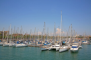 Fototapeta premium View from Rambla De Mar of the marina & many yacths moored at Port Vell which is a waterfront harbor and part of the Port of Barcelona, Catalonia, Spain.
