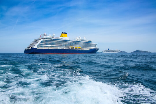 Cruise ship at anchor ourside St Peter Port, Guernsey. Large ship with blue hull and yellow funnel, and white ship in the distance, off the coast of the Channel Islands, UK.