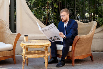 Young businessman reading newspaper in outdoor cafe