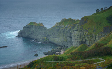 Muroran, Hokkaido, Japan - Oct 04 2024, panoramic aerial view of the picturesque Pacific ocean coast with sharp cliffs and high mountain slopes, in a storm, it's raining, at daytime, Muroran, Japan
