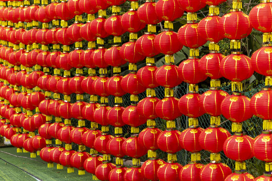 View of vibrant red lanterns hanging in rows against a backdrop of green foliage, creating a festive atmosphere, Kuala Lumpur, Federal Territory of Kuala Lumpur, Malaysia.