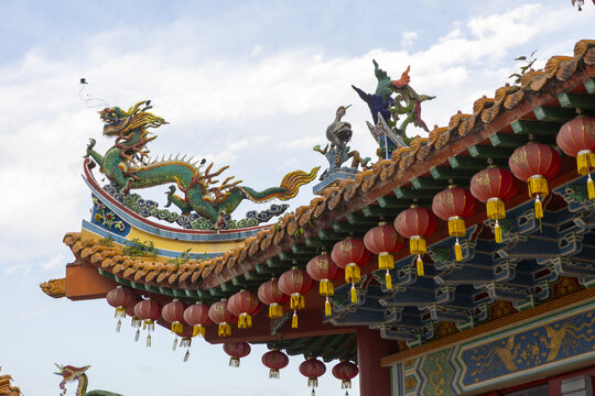 View of ornate temple roof adorned with a vibrant green dragon, red lanterns, and intricate carvings against a bright sky, Kuala Lumpur, Federal Territory of Kuala Lumpur, Malaysia.