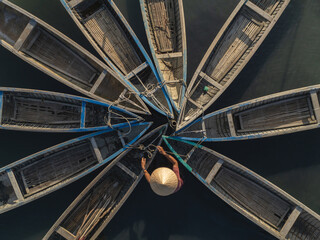 Aerial view of a person wearing a conical hat standing amidst a cluster of boats in a starburst pattern, Tuy An, Phu Yen, Vietnam