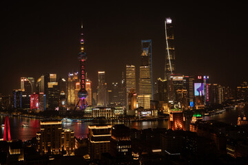 View of a dazzling skyline ablaze with vibrant lights reflecting on the dark waters of the river at night, Shanghai, Shanghai, China.