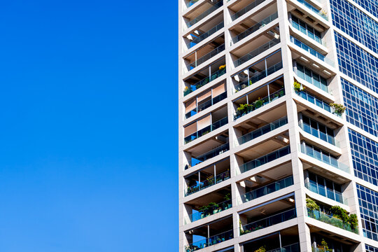 Close-up facade of modern residential building with balconies. Futuristic architecture in Tel Aviv against a blue sky, Israel.