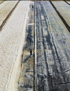 Aerial view of salt fields showcasing contrasting textures and tones under the sun, Phuoc Diem, Ninh Thuan, Vietnam.