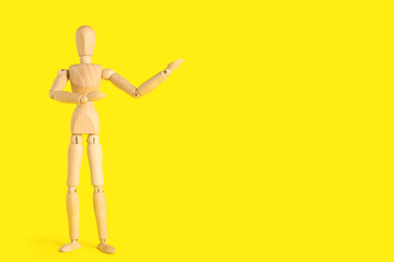 Wooden mannequin showing something on yellow background