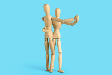 Wooden mannequins dancing on blue background