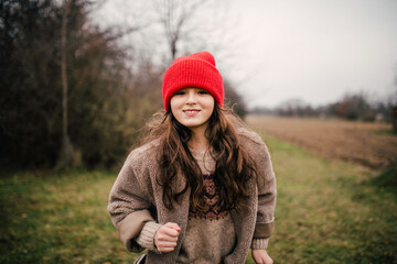 Naklejka premium Preteen girl on walk nature wearing red hat.