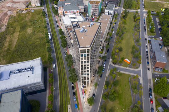 Aerial view of a striking triangular building piercing the cityscape, flanked by verdant trees and pathways, showcasing a blend of modern architecture and natural beauty, Bremen, Bremen, Germany.