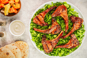Middle Eastern traditional dish with grilled juicy lamb chops/ribs placed on bed of fresh chopped...