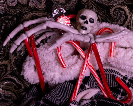 A haunted Christmas scene featuring peppermints, candy canes, skulls and a skeleton hand. 