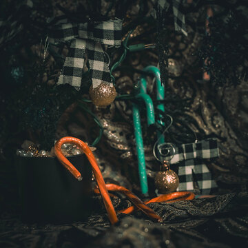 Dark Christmas Tree with black and white bows as ornaments. The photograph is hazy as to apply a haunted theme. There are also colorful candy canes as decoration to compliment.