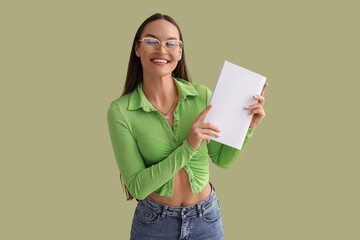 Young woman with blank magazine on green background