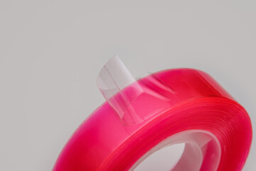 A detailed macro shot captures the glossy transparent plastic adhesive tape peeling back from the vibrant pink core roll. Ideal for DIY projects.