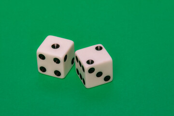 A pair of classic white gambling dice rests firmly on the vibrant green felt ground. State to luck, risk or probability in a high-stakes game. Great for betting concepts.
