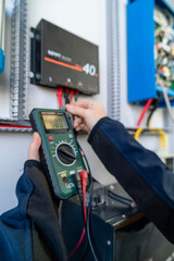 Technician measuring solar charge controller voltage with multimeter